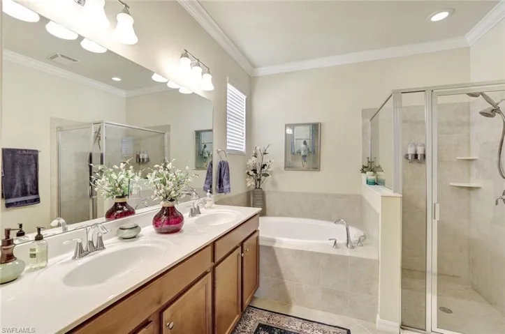 Bathroom with ornamental molding, vanity, tile patterned floors, and plus walk in shower