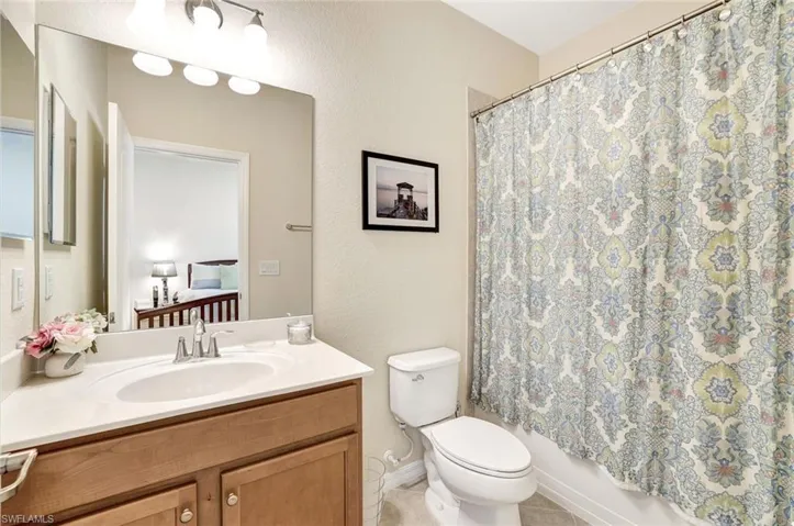 Full bathroom featuring vanity, shower / bath combo, tile patterned floors, and toilet