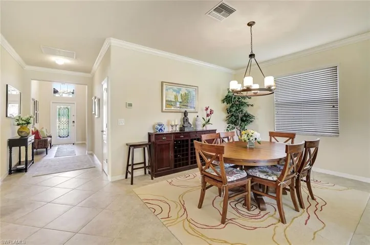 Tiled dining space featuring crown molding and an inviting chandelier