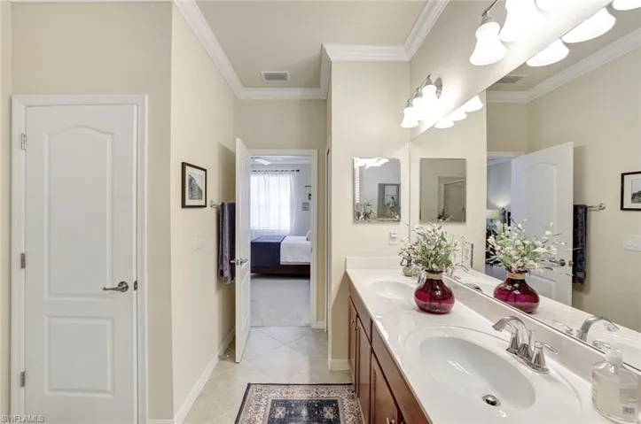Bathroom with crown molding, tile patterned floors, and vanity