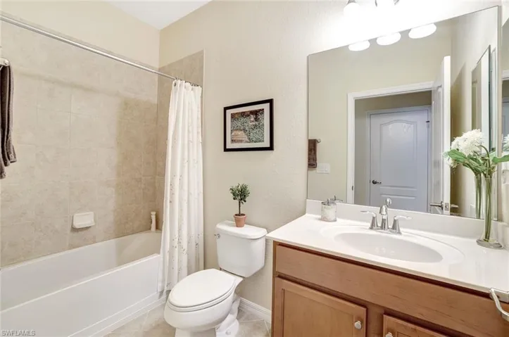 Full bathroom featuring toilet, tile patterned floors, shower / bathtub combination with curtain, and vanity