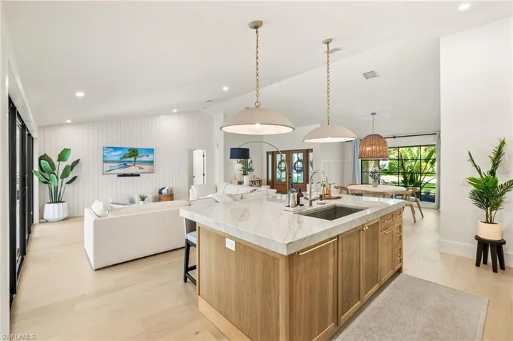 Kitchen with light wood-style floors, open floor plan, a kitchen island with sink, brown cabinets, and recessed lighting