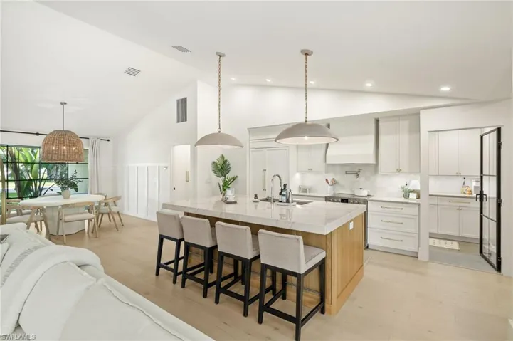 Kitchen featuring open floor plan, a kitchen breakfast bar, stainless steel stove, high vaulted ceiling, and light wood finished floors