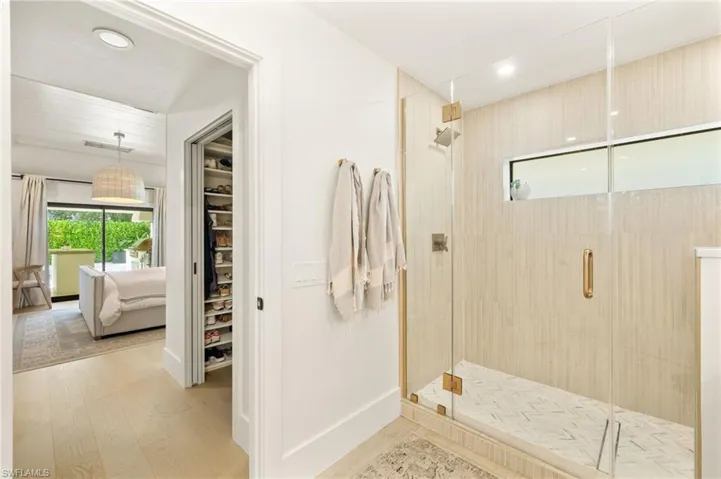 Ensuite bathroom featuring a shower stall, wood finished floors, a walk in closet, and recessed lighting