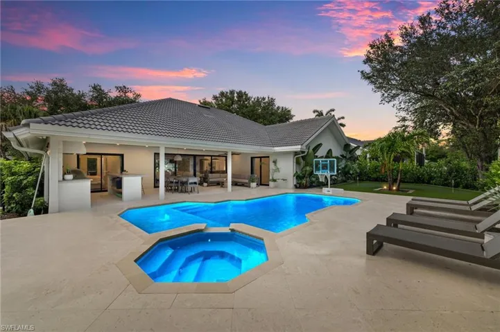 Pool at dusk with a patio, outdoor lounge area, and a pool with connected hot tub