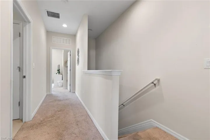 Hallway featuring light colored carpet