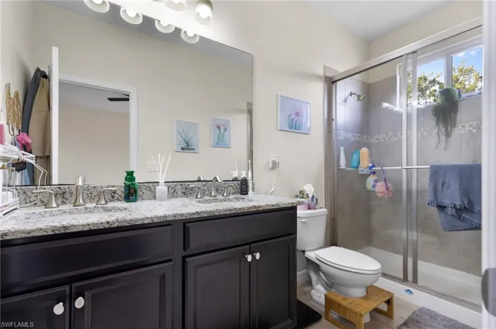 Bathroom with a shower with door, vanity, and toilet