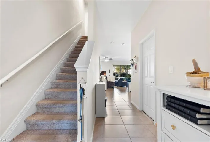 Stairs with tile patterned floors and ceiling fan