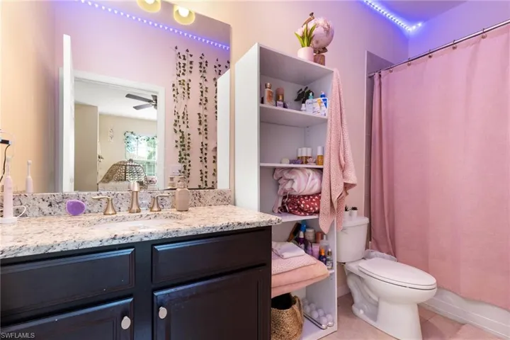 Bathroom with vanity, ceiling fan, tile patterned floors, and toilet