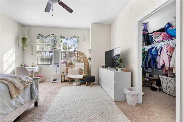 Carpeted bedroom featuring a spacious closet, a closet, and ceiling fan