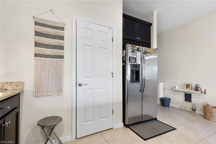 Kitchen featuring light stone counters, light tile patterned floors, and stainless steel refrigerator with ice dispenser