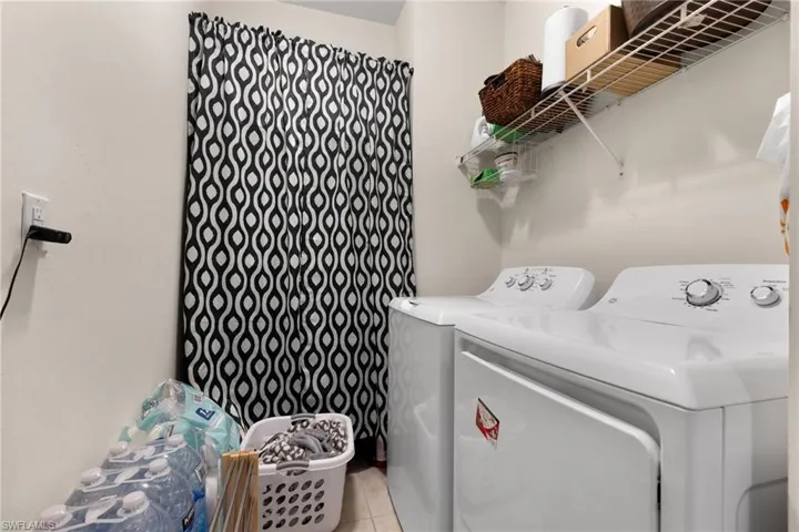 Laundry area with light tile patterned floors and washer and clothes dryer