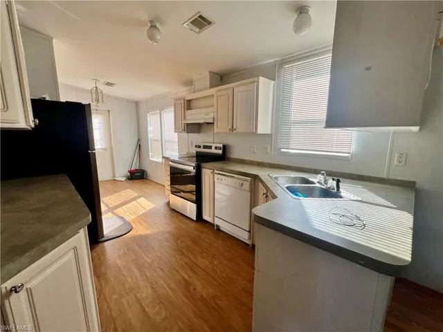 Kitchen with stainless steel appliances, light wood finished floors, dark countertops, and ornamental molding