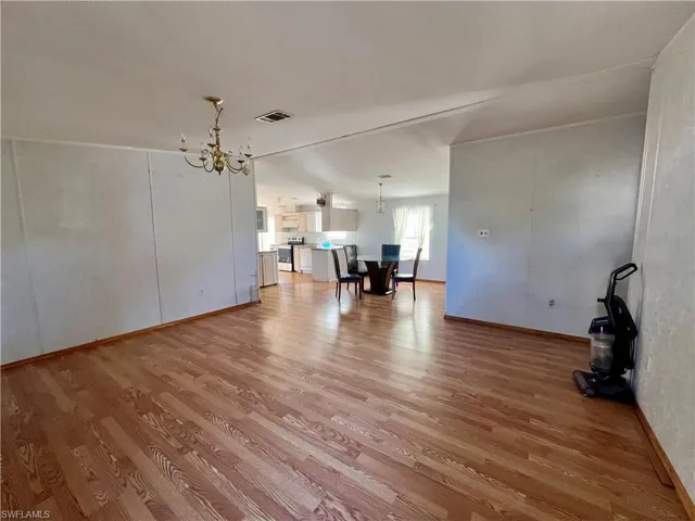 Unfurnished living room featuring hanging lights and light wood finished floors