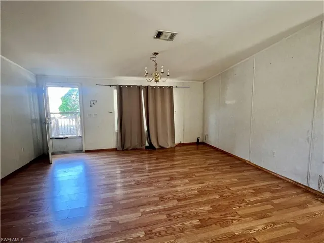 Unfurnished room featuring wood finished floors, suspended lighting, and a decorative wall