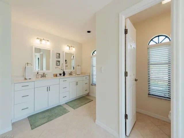 Full bathroom with baseboards, double vanity, a sink, and tile patterned floors