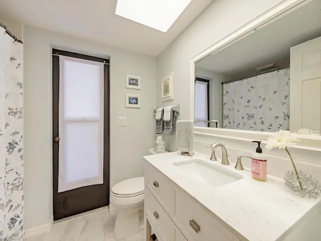Full bath featuring a shower with curtain, toilet, and vanity