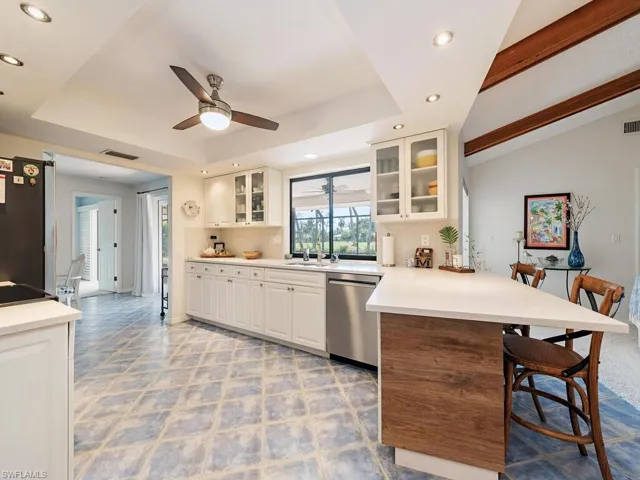 Kitchen with a kitchen breakfast bar, stainless steel dishwasher, a raised ceiling, freestanding refrigerator, and a peninsula