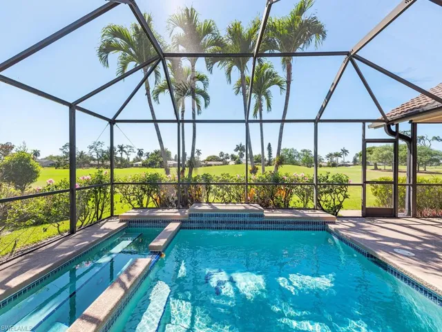View of pool featuring glass enclosure, a pool with connected hot tub, and a patio area
