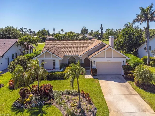 View of front of house featuring a chimney, a garage, stucco siding, a front lawn, and driveway