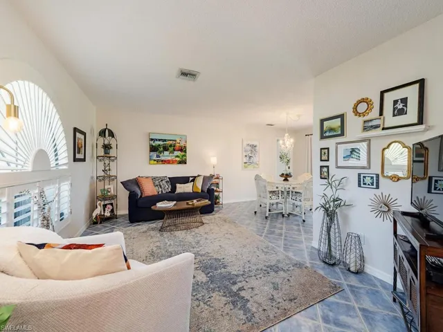 Living room featuring a textured ceiling, visible vents, baseboards, an inviting chandelier, and tile patterned flooring