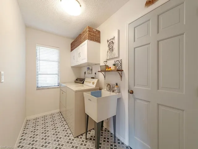 Laundry room featuring cabinet space, baseboards, separate washer and dryer, and a textured ceiling