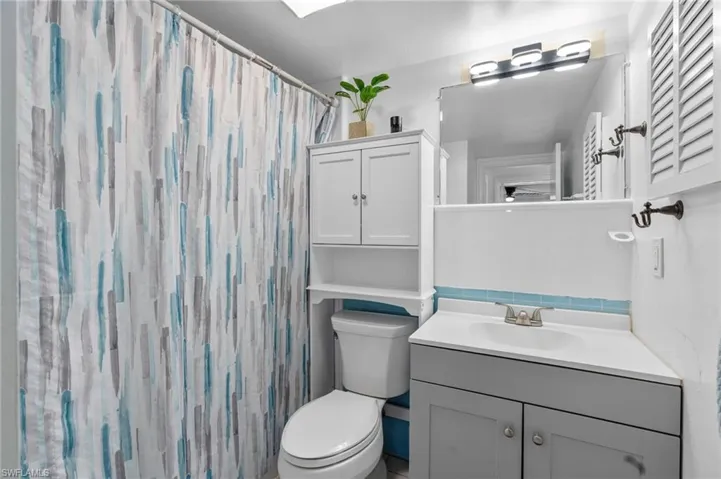 Bathroom featuring a shower with curtain, toilet, and vanity