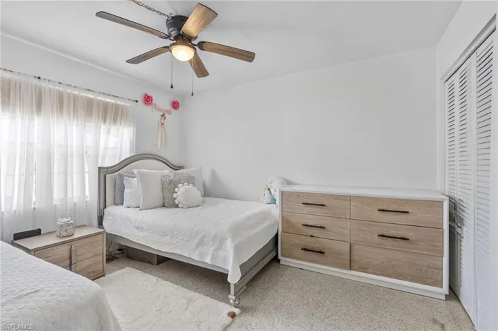 Bedroom featuring a closet, light speckled floor, and a ceiling fan
