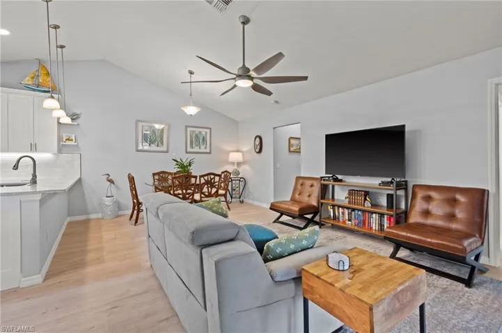 Living room featuring lofted ceiling, sink, ceiling fan, and light hardwood / wood-style flooring
