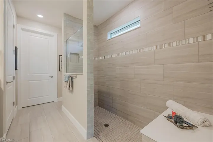 Bathroom with tile walls, a tile shower, and tile flooring