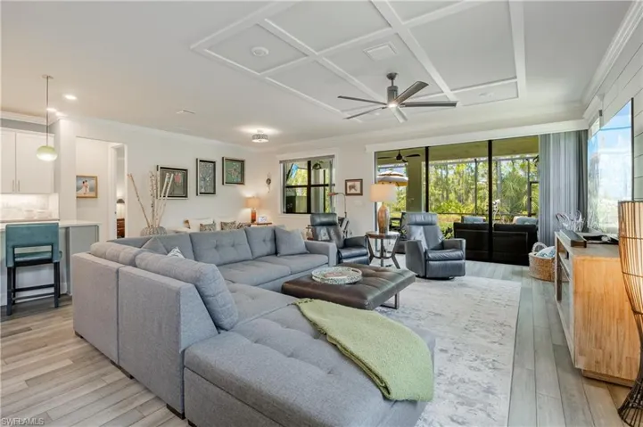 Living room featuring coffered ceiling, ceiling fan, light wood-type flooring, and ornamental molding