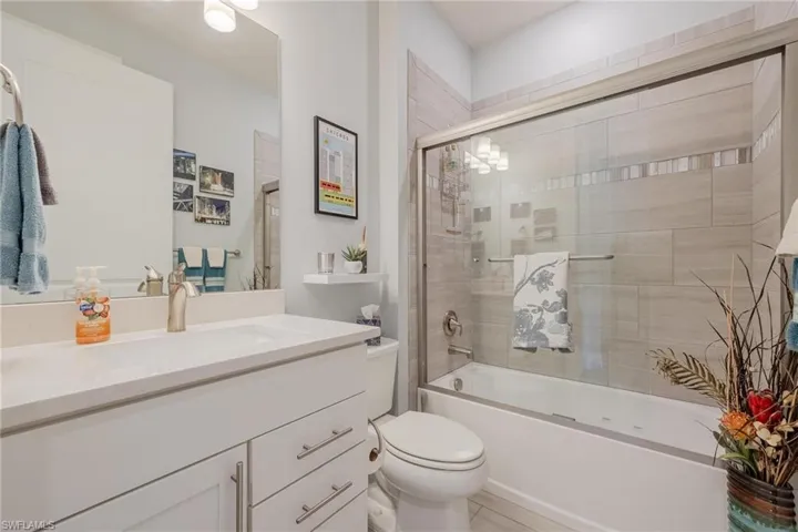 Full bathroom with combined bath / shower with glass door, oversized vanity, and toilet