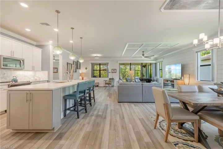 Kitchen featuring backsplash, ceiling fan, light hardwood / wood-style floors, and a kitchen island with sink