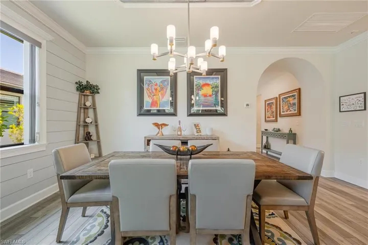 Dining space with light hardwood / wood-style floors, ornamental molding, and an inviting chandelier