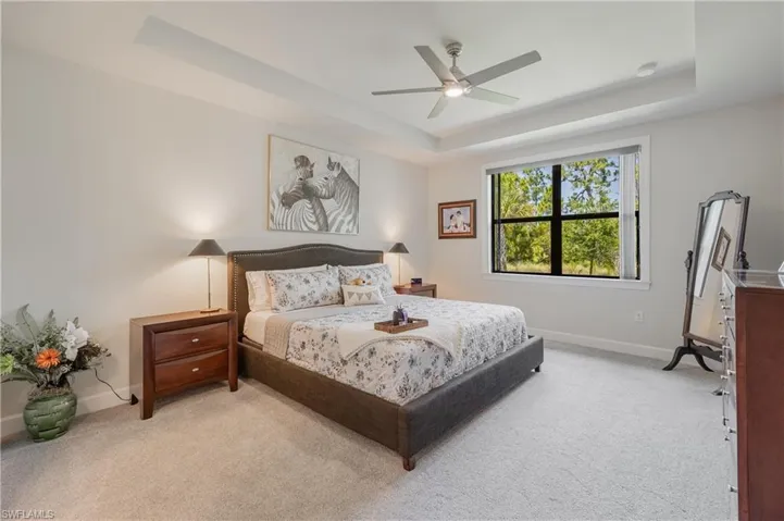 Bedroom with ceiling fan, a raised ceiling, and carpet floors