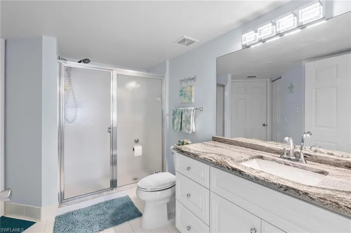 Bathroom featuring tile patterned flooring, walk in shower, vanity, and toilet