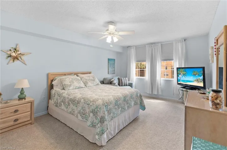 Carpeted bedroom with ceiling fan and a textured ceiling