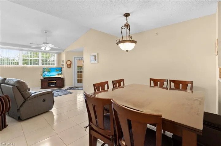 Dining room featuring lofted ceiling, ceiling fan, light tile patterned floors, and a textured ceiling