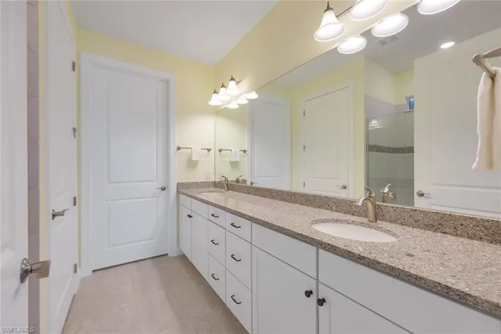 Bathroom with vanity, a tile shower, and tile patterned floors
