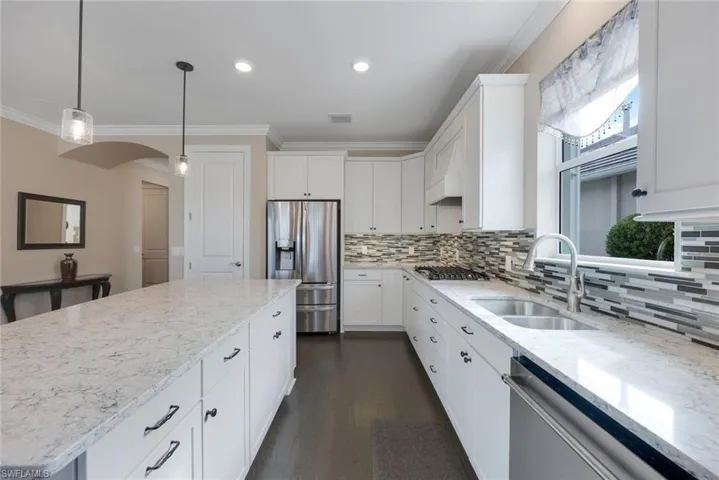 Kitchen with sink, stainless steel appliances, hanging light fixtures, a center island, and white cabinetry