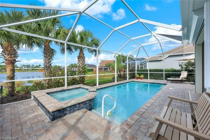 View of pool featuring a water view, a patio, an in ground hot tub, and a lanai
