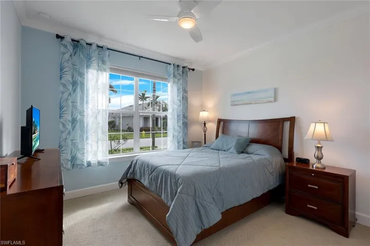 Carpeted bedroom featuring ceiling fan and crown molding