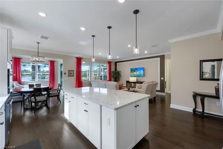 Kitchen with pendant lighting, light stone countertops, dark hardwood / wood-style floors, and white cabinetry