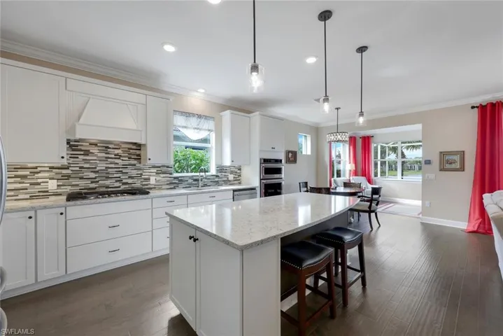 Kitchen featuring a kitchen island, dark hardwood / wood-style flooring, hanging light fixtures, white cabinets, and ornamental molding