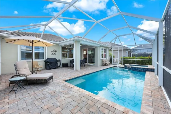 View of swimming pool with a lanai, a grill, an in ground hot tub, and a patio area
