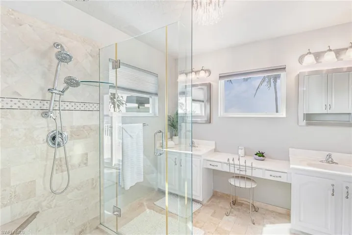 Bathroom featuring vanity, a stall shower, and a chandelier