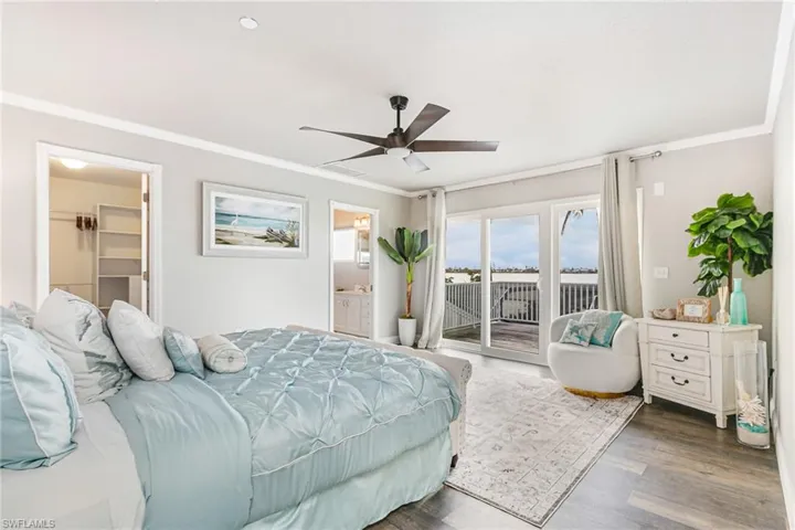 Bedroom featuring ornamental molding, access to exterior, ceiling fan, a walk in closet, and wood finished floors