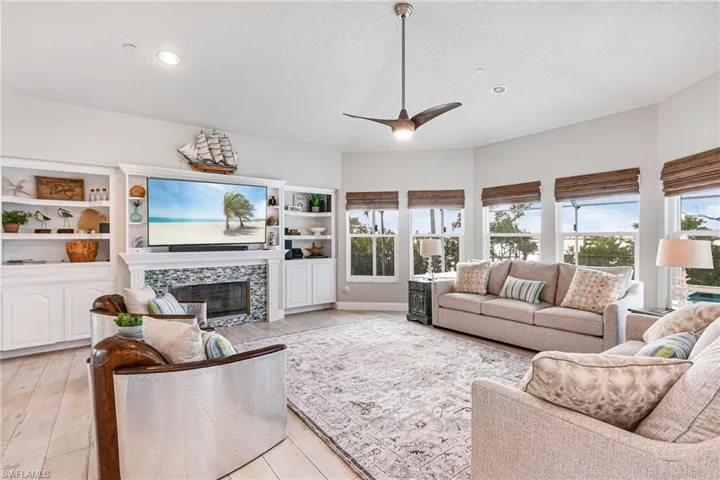 Living room with a tiled fireplace, ceiling fan, light wood-type flooring, a textured ceiling, and recessed lighting