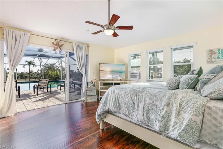 Bedroom featuring hardwood / wood-style floors, access to exterior, a sunroom, and a ceiling fan
