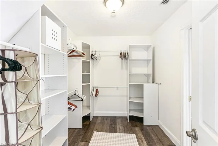 Walk in closet with dark wood-style floors